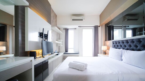 Et hotelværelse med en seng, et fjernsyn, et skrivebord og et vindue.