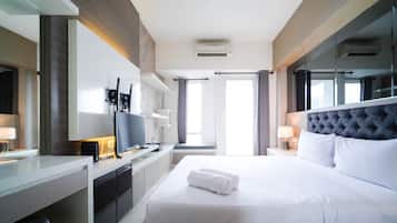 A hotel room with a bed, a TV, a desk, and a window.