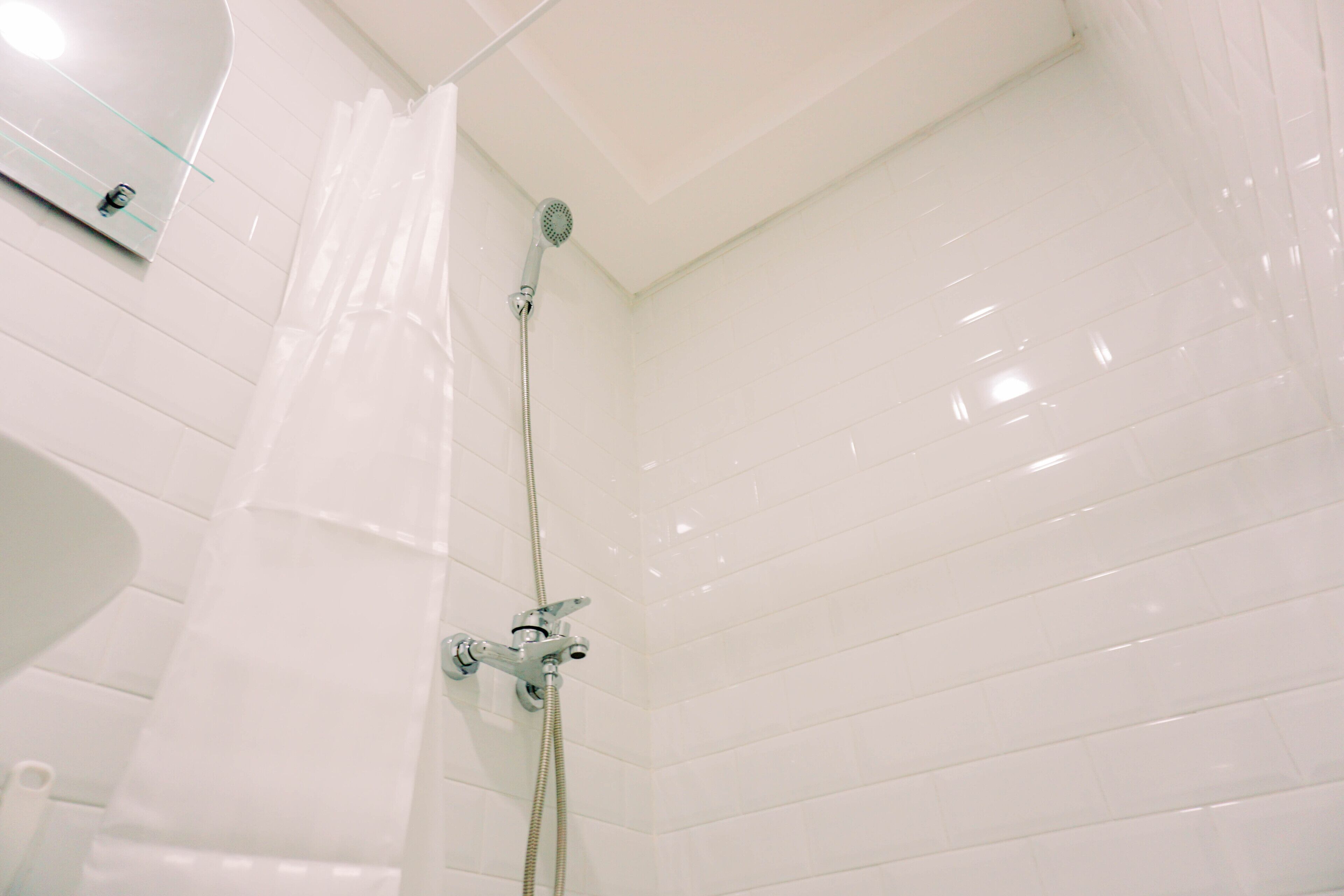 A shower with a glass enclosure, a handheld showerhead, and a wall-mounted faucet.