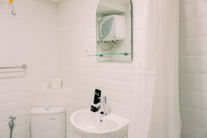 A bathroom with a white toilet, a sink, a glass shower enclosure, and a mirror above the sink. - Modern And Cozy Studio Loft Apartment At Kingland Avenue (South Tangerang)