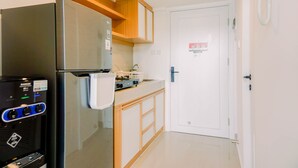 A compact kitchen with a refrigerator, a microwave, and a sink. - Modern And Cozy Studio Loft Apartment At Kingland Avenue (South Tangerang)