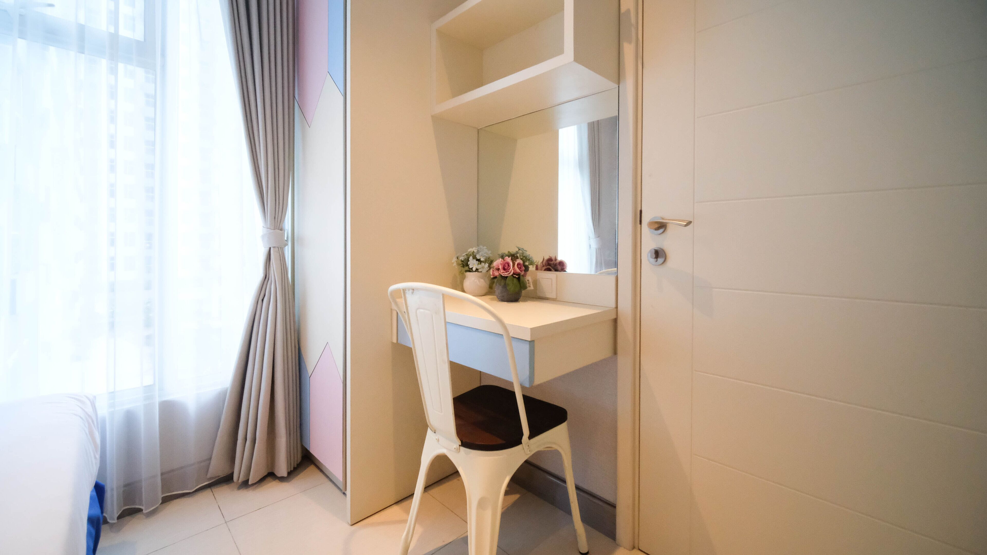A bathroom with a white vanity, a mirror, and a chair.