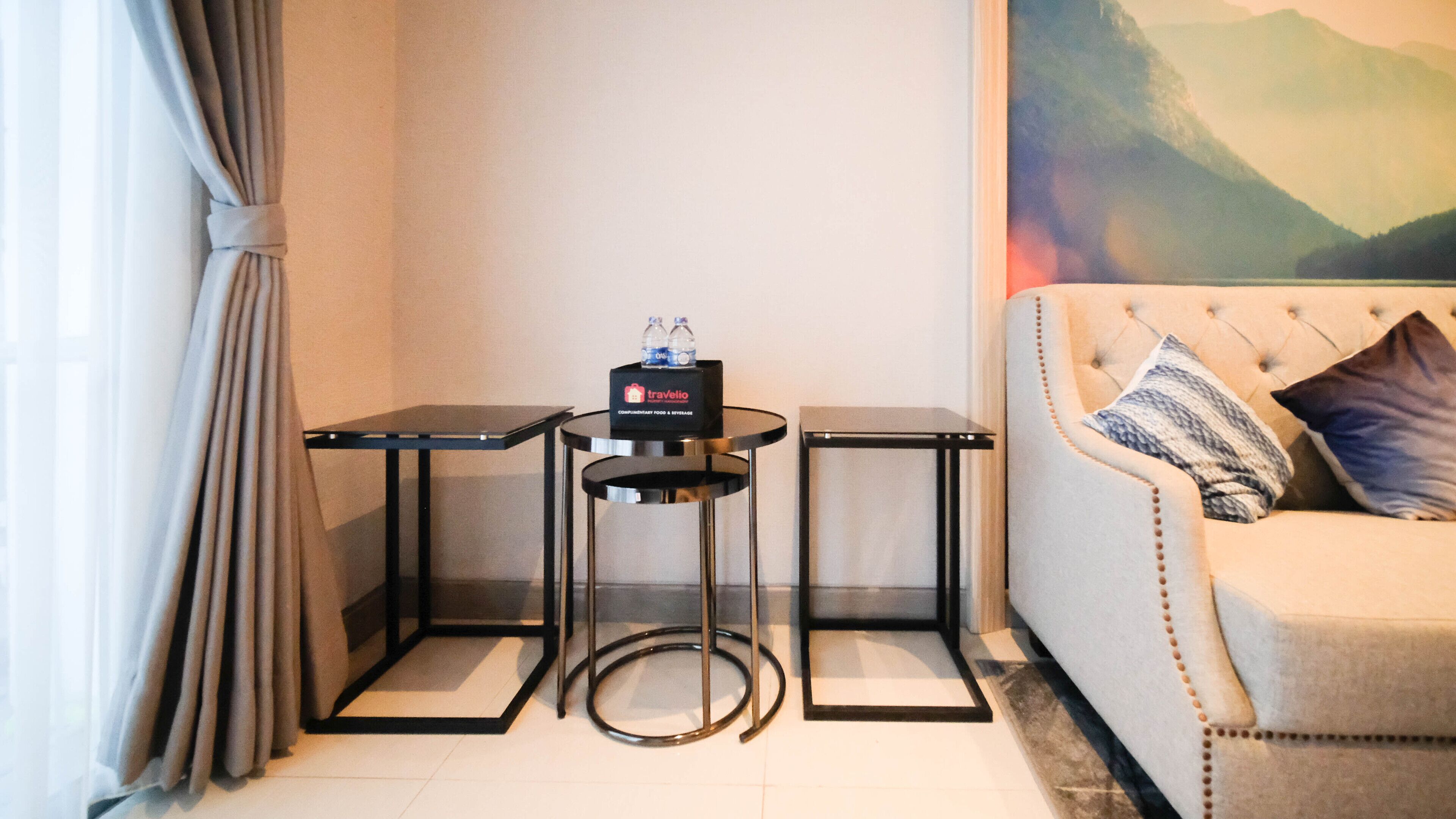 A small, modern room with a sofa, two black tables, and a travel service sign.