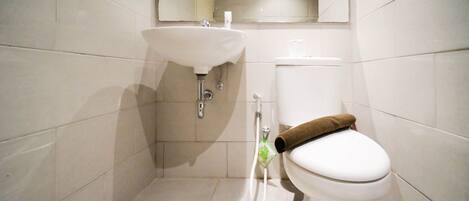 A bathroom with a white sink, toilet, and a shower area.