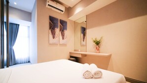 A hotel room with a bed, a mirror, a vase with flowers, and artwork on the wall. - Cozy Living 2Br At Anderson Supermall Mansion Apartment (Surabaya)