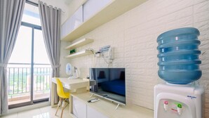 Habitación moderna con televisión, dispensador de agua y balcón con cortinas.
