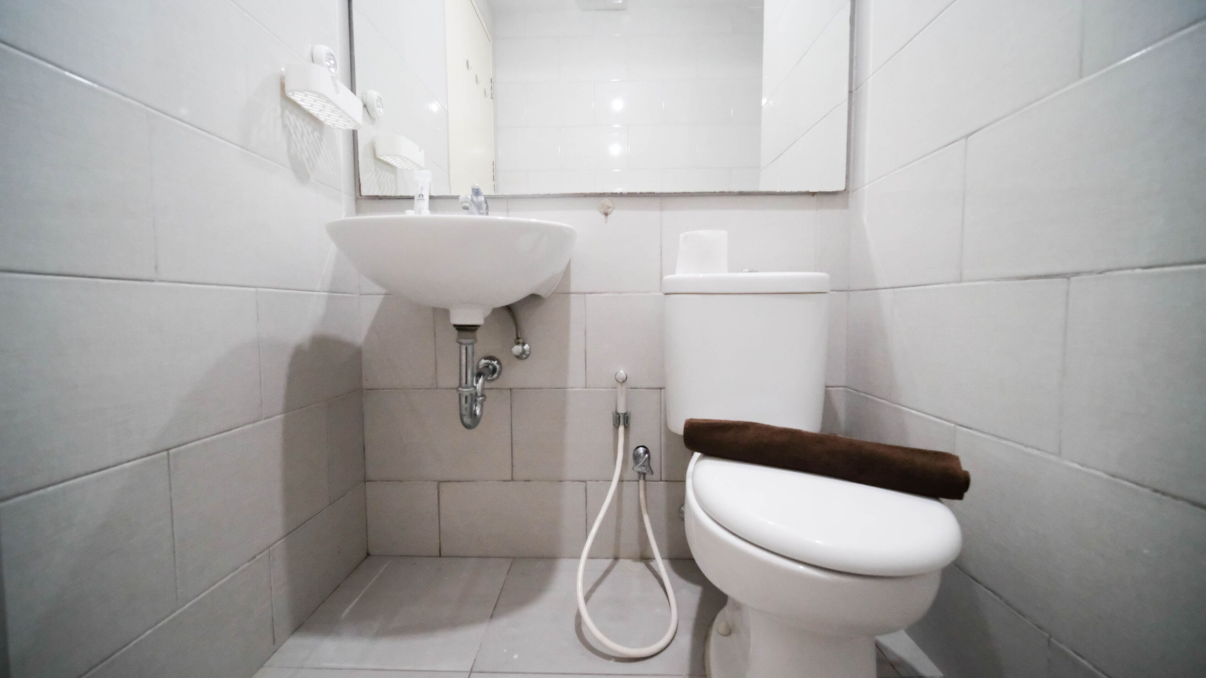 A small, modern bathroom with a white sink, a toilet, and a mirror above the sink.
