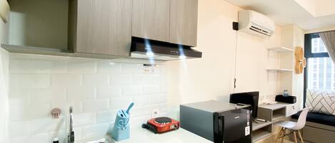 Una cocina moderna con un lavamanos de acero inoxidable, un refrigerador negro y armarios de madera.