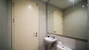 Un baño moderno con lavamanos, inodoro y un espejo grande.