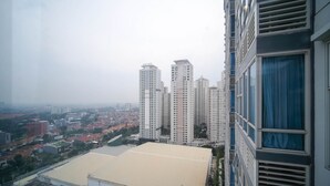 Un edificio de gran altura con varios pisos, ventanas amplias y vistas a un paisaje urbano con diversos edificios y una antena parabólica en el techo.