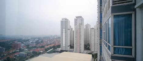 A high-rise building with multiple floors, large windows, and a view of a cityscape with various buildings and a satellite dish on the roof.