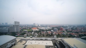 Un paisaje urbano con una mezcla de edificios de gran altura y viviendas residenciales, un amplio espacio abierto con estructuras, y una vista distante del horizonte de la ciudad.