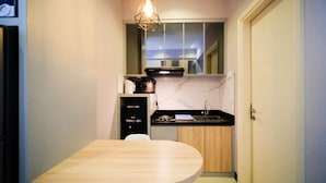 Una cocina pequeña con una mesa de madera, horno empotrado, lavamanos y cocina compacta.