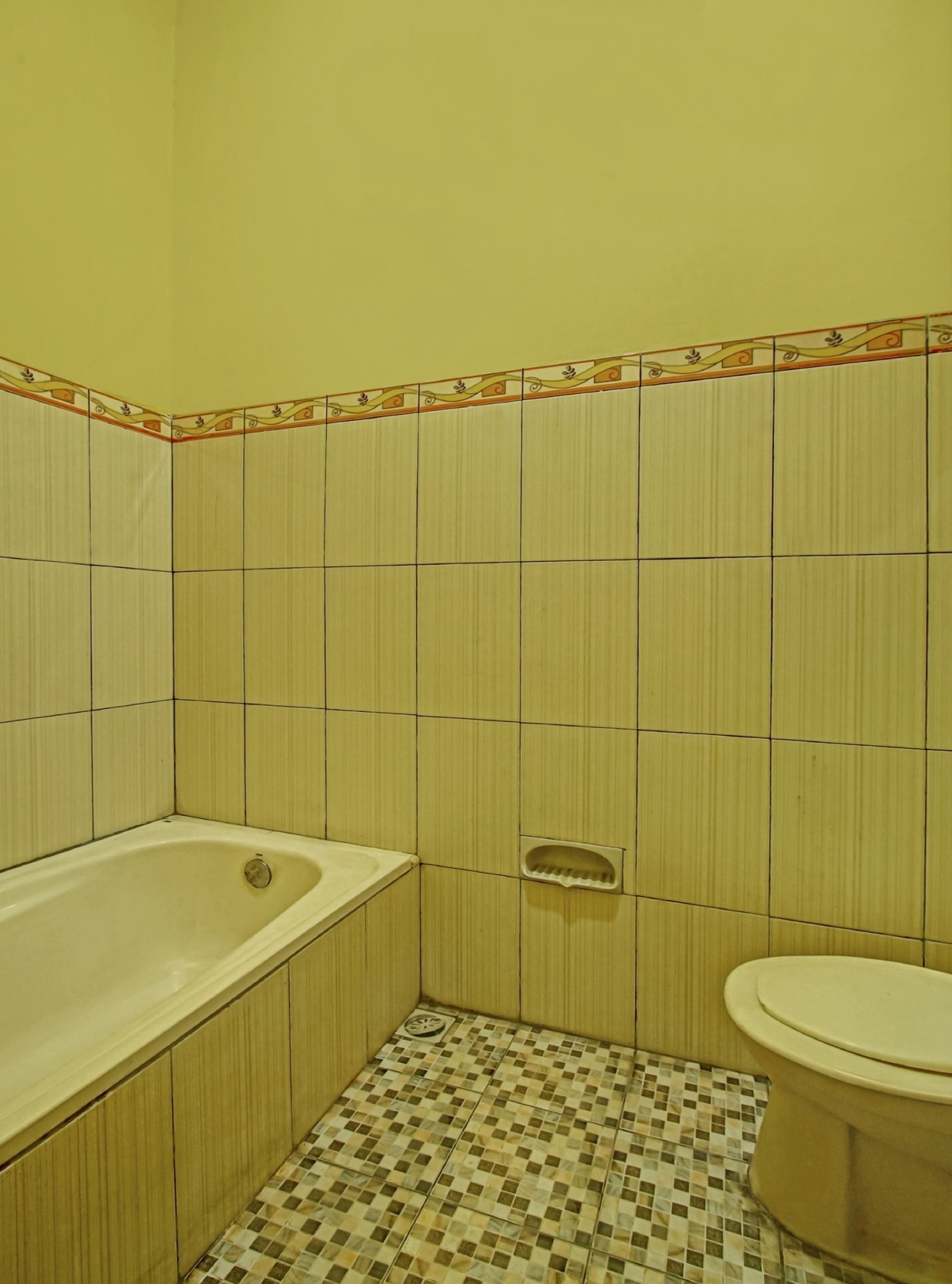 Un baño con bañera, inodoro y suelo de baldosas a cuadros.