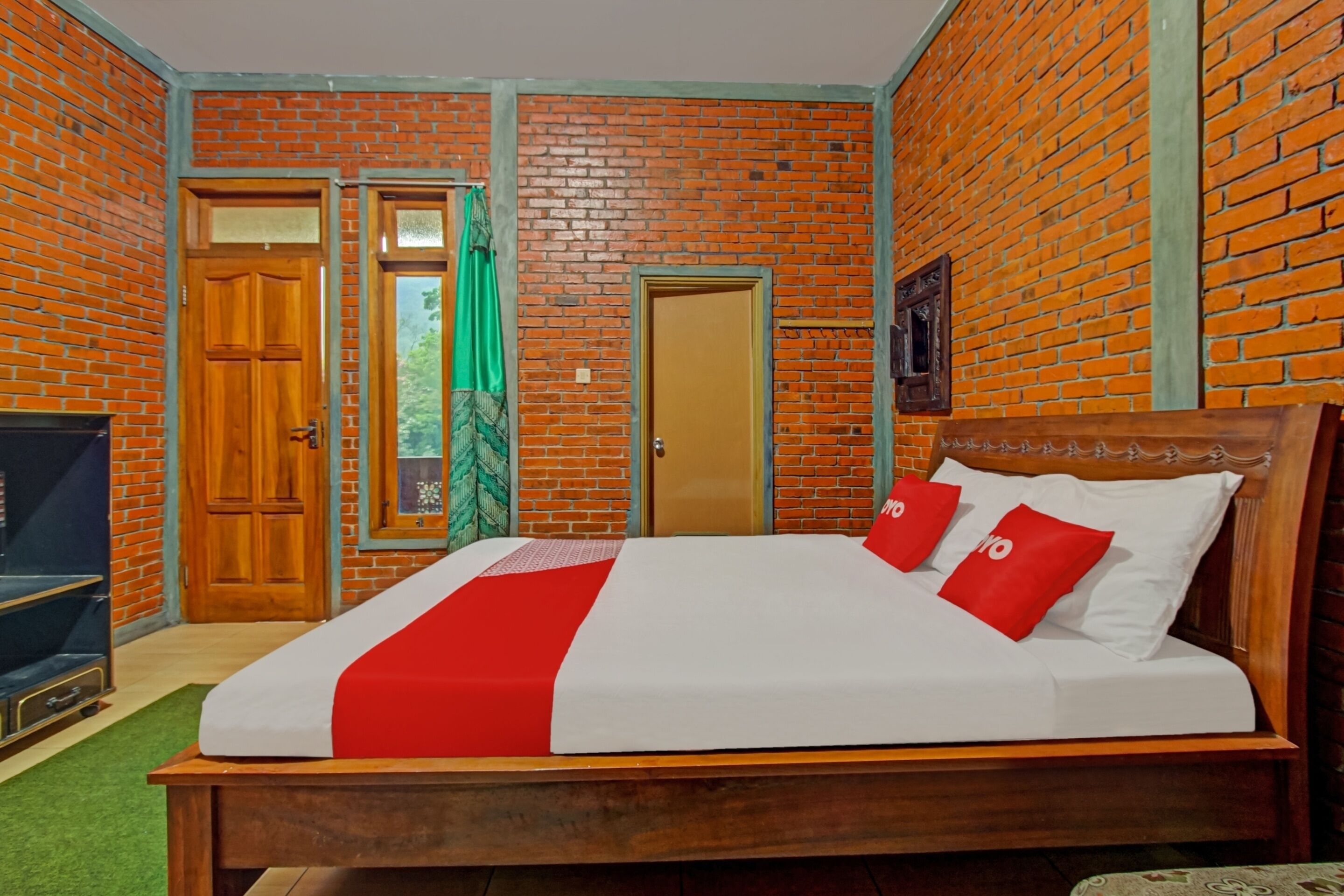Una stanza con un letto di legno, una tenda verde e un muro in mattoni.