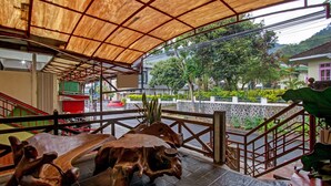 A covered outdoor area with a wooden sculpture, a staircase, and a view of a residential street. - Hotel O Villa Papada (Batu)