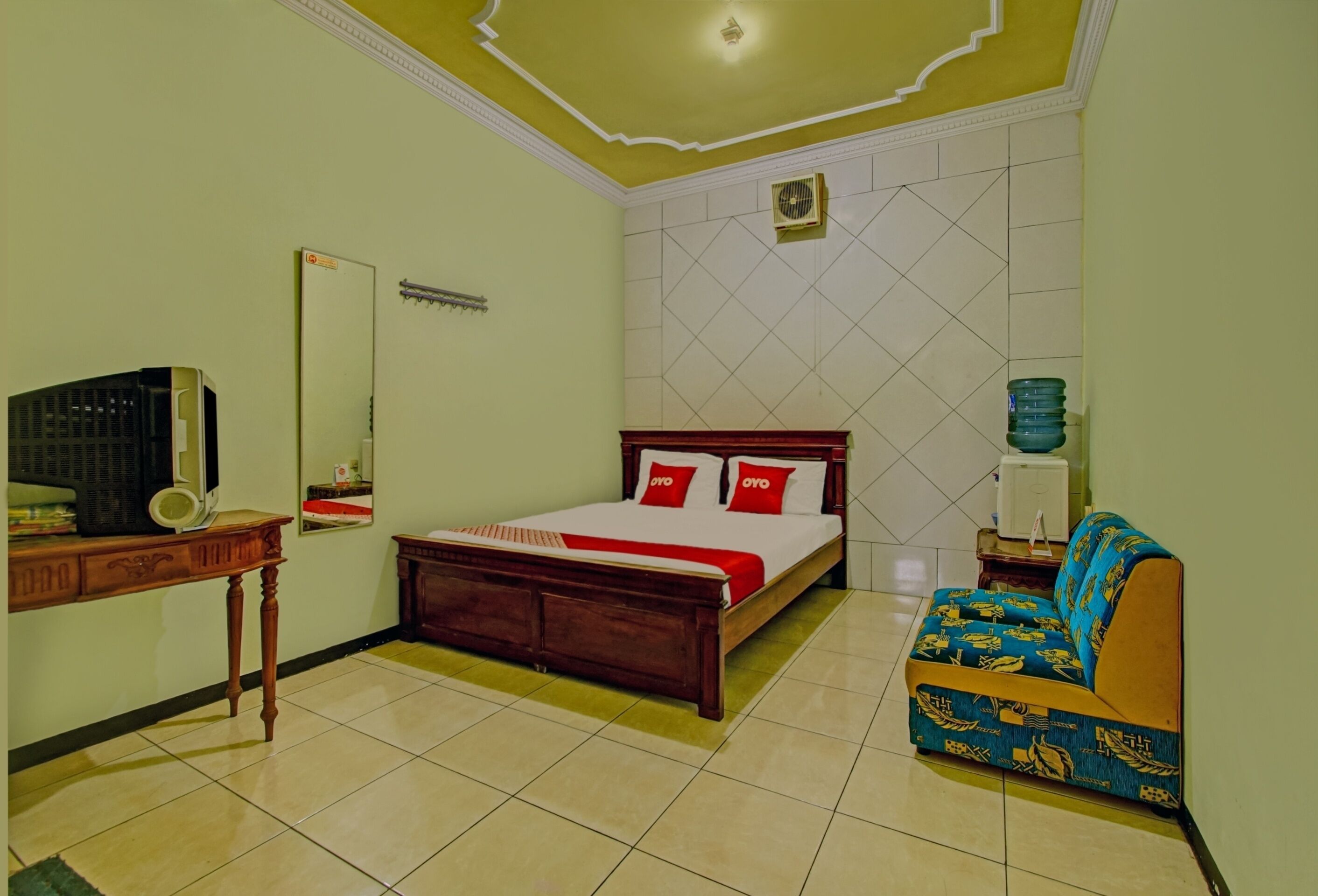Un dormitorio con cama, sofá, escritorio y espejo.