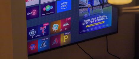 Una pantalla de televisión mostrando varios logotipos de servicios de streaming y un anuncio deportivo.