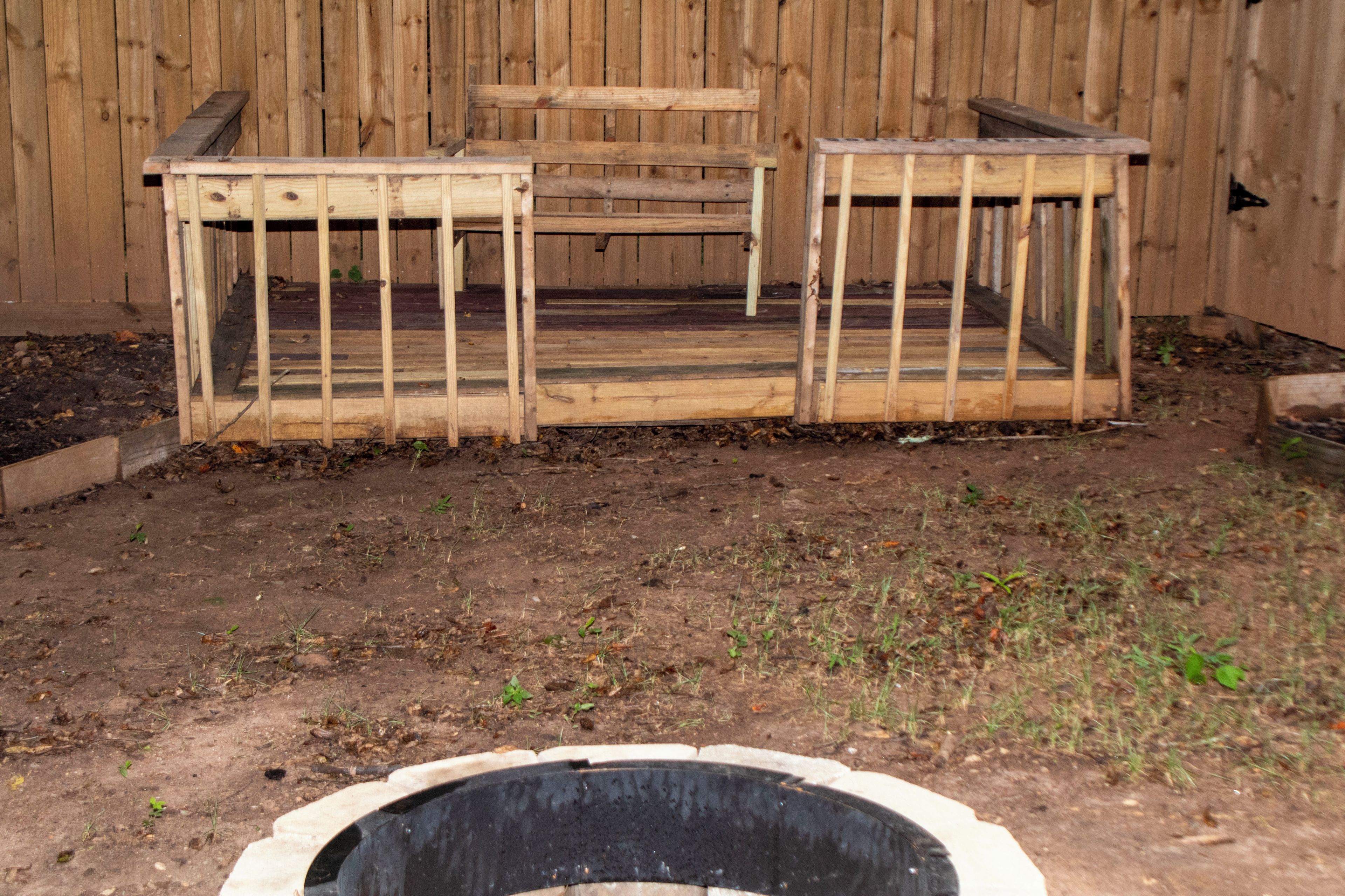 A wooden outdoor seating area with a raised platform and a black circular object in the foreground.