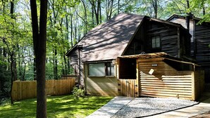 A wooden cabin with a sloped roof, a gravel driveway, and a wooden fence. - Cheerful cabin, tucked away, for nature lovers. (Decatur)