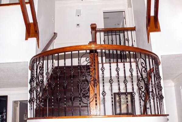 Una escalera de madera con barandilla de hierro forjado y un marco en la pared.