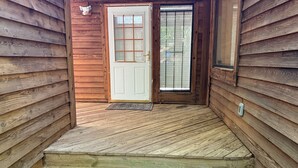 A wooden cabin with a front door, a small porch, and a window. - Cheerful cabin, tucked away, for nature lovers. (Decatur)