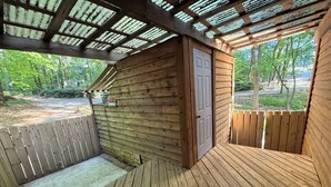 A wooden deck with a covered area, a door, and a view of a wooded area. - Cheerful cabin, tucked away, for nature lovers. (Decatur)