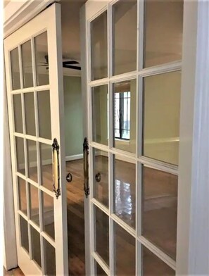 Una habitación con una puerta blanca grande que tiene paneles de vidrio y un picaporte.