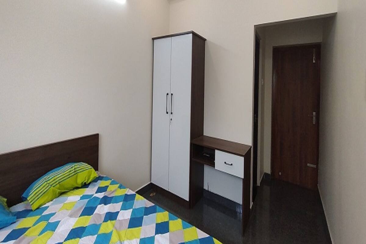 A bedroom with a bed, a wardrobe, a desk, and a door.