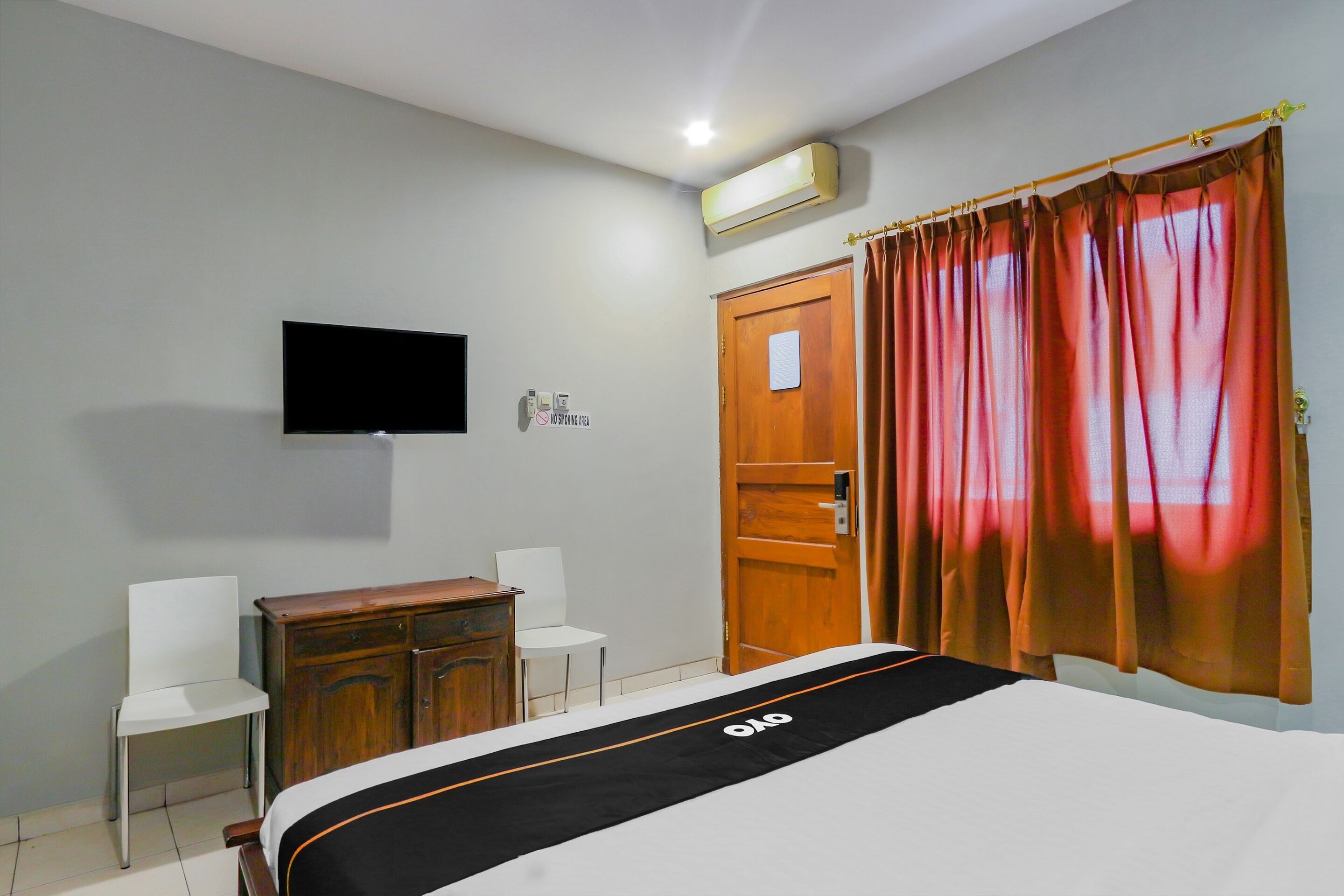 A bedroom with a bed, a television, a wardrobe, and a desk.