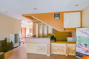 A reception area with a staircase, a reception desk, a clock, and a poster. - Hotel O Istana Griya 2 Hotel (Surakarta)