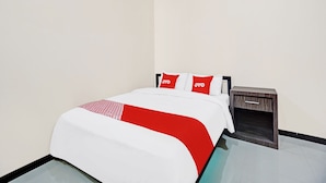 A hotel room with a bed, a nightstand, and a small wooden cabinet. - Hotel O Avisha Guest House Syariah (Malang)