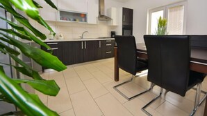 Une cuisine moderne avec des meubles de couleur sombre, un plan de travail blanc et un coin repas avec des chaises noires.