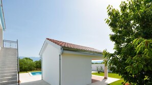 Une maison moderne dotée d’une piscine, d’un patio couvert et offrant une vue sur les montagnes.