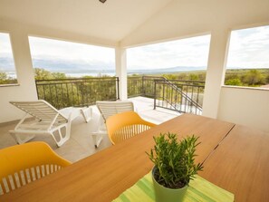 A balcony with a view of the countryside, a wooden table, and two chairs. - Vacation home Elena by Interhome (Novigrad (Zadar))