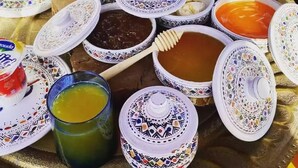 A table with various dishes and a glass of green drink, likely a traditional meal setting.