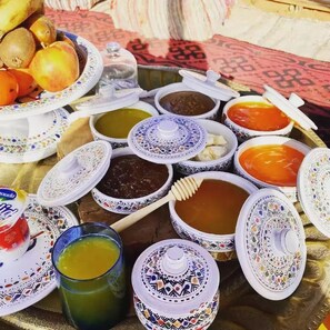 Ein Tisch mit verschiedenen Gerichten und einem Glas grünes Getränk, vermutlich eine traditionelle Mahlzeit.
