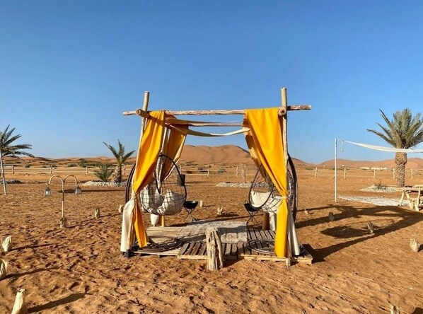 Paisaje desértico con una estructura de madera decorada con tela amarilla.