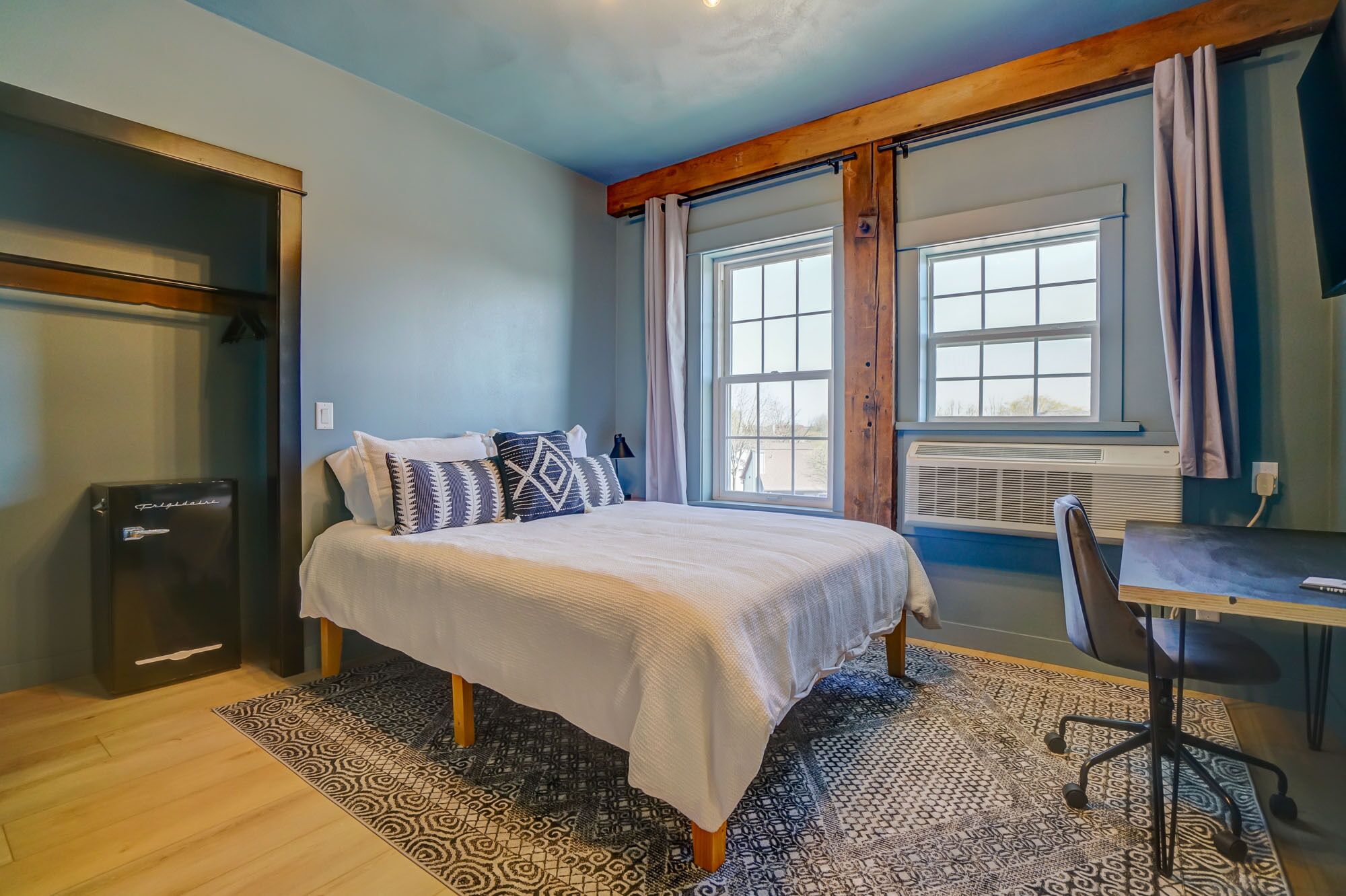 A bedroom with a bed, a desk, and a chair.