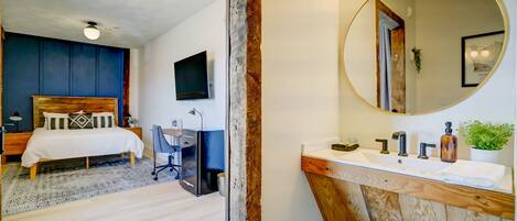 A modern bedroom with a bed, desk, and TV.