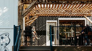 Een terras met metalen stoelen en een houten pergola.