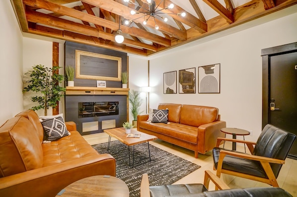 A living room with a fireplace, leather sofa, wooden coffee table, and a black leather armchair.