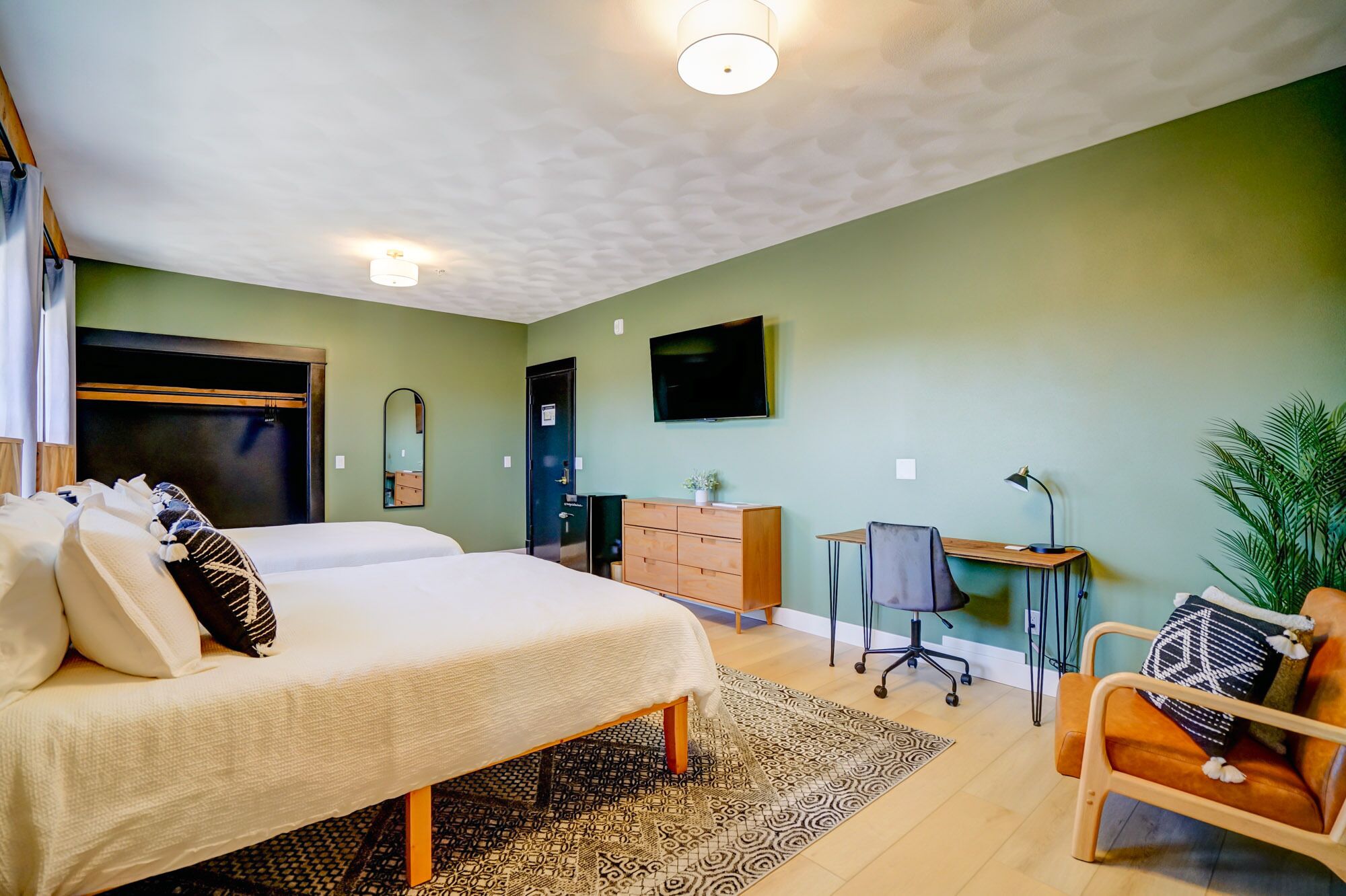 Habitación de hotel con dos camas, un escritorio, una silla, un televisor y un aparador.