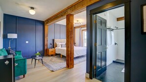 Een moderne slaapkamer met een houten plafond, een groot bed en uitzicht op de badkamer.
