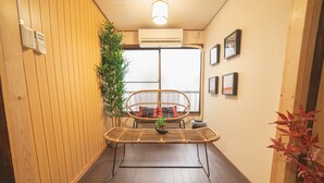 A narrow hallway with a wooden floor, a wicker chair with cushions, a potted plant, and a wall-mounted air conditioner. - Asakusa, Tokyo Sky Tree (墨田区)