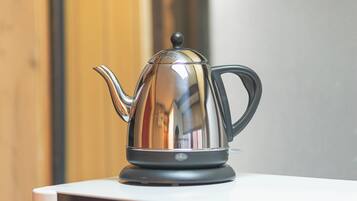 A stainless steel kettle on a white surface.
