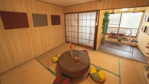 A tatami mat room with a round table, sliding doors, and a view of a balcony. - Asakusa, Tokyo Sky Tree (墨田区)