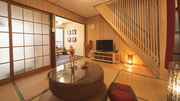 A traditional Japanese-style living room with tatami flooring, a low wooden table, a television, and a staircase. - Asakusa, Tokyo Sky Tree (墨田区)