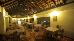 A restaurant with high ceilings, tiled floors, and tables set with chairs. - Hotel Vijayetha (Nagercoil)