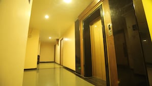 A hallway with an elevator and a door with a sign. - Hotel Vijayetha (Nagercoil)